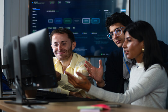Software Development Team Working Together at Computer, Discussing Programming Solutions, Reviewing Technical Information and Solving Application Development Problems at desk in office.