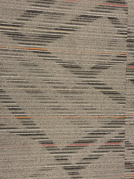 Gray commercial carpet tile with orange and red stripe pattern closeup