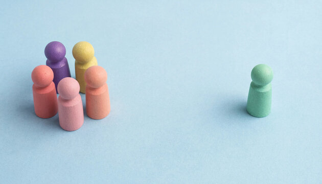 Social exclusion concept with colorful wooden figures one isolated from group on light blue background