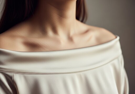 Close up of a woman wearing a soft beige off the shoulder top with elegant neckline
