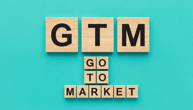 GTM go to market concept spelled with wooden letter blocks on teal background