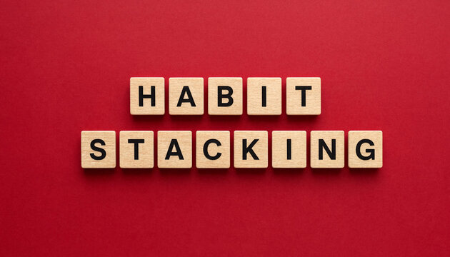 Habit stacking concept spelled with wooden letter blocks on red background for productivity and behavior change