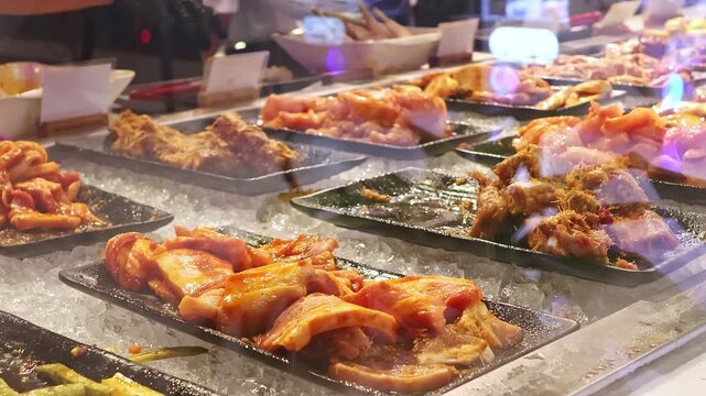 Kitchen staff placing prepared seafood on serving trays at Vietnamese unlimited buffet. Freshly cooked dishes are arranged on trays over ice.