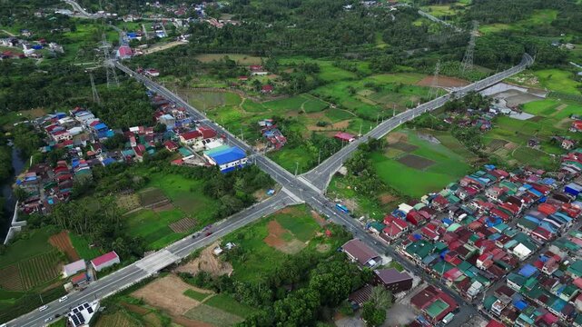 Pullback drone reveal showcasing Lucban Bypass Road, peaceful farming communities, fertile rice fields agricultural land, within the protected mountain landscape at Lucban, Quezon Philippines.