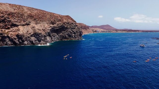 Aerial view of an offshore fish farm beside the volcanic coast near Los Cristianos, Tenerife, surrounded by deep blue Atlantic waters