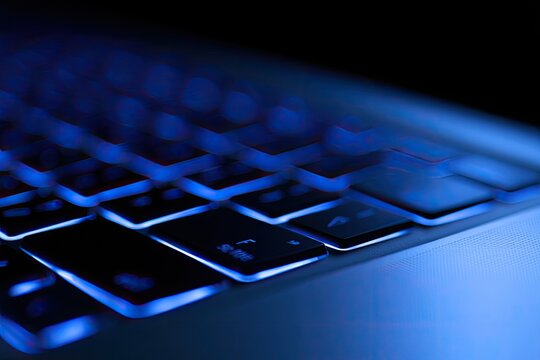 Illuminated keyboard keys glowing with cool blue light in darkness