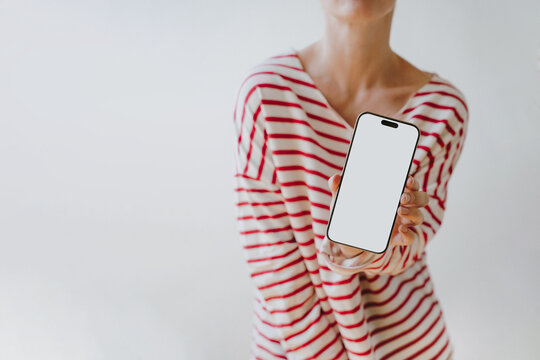 Horizontal Shot Of Woman In Striped Shirt Presenting Mobile Phone With Blank Screen Mockup