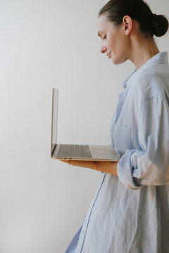 Young Female Professional Standing In Side Profile Typing On Silver Laptop Computer