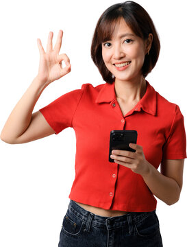 Happy smiling asian woman holding smartphone showing okay gesture wearing red shirt isolated on transparent background cutout stock photo