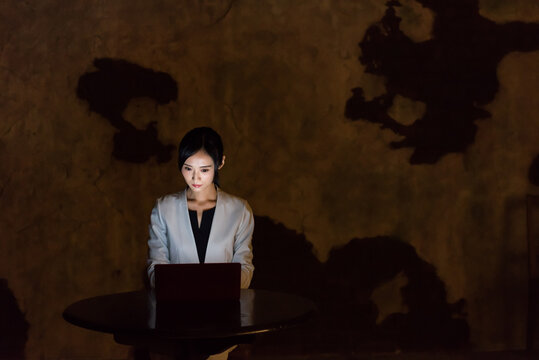 A woman using a computer in a dark room. PC, dark, crime, crime prevention, security, risk, hacker, darkness, internet.