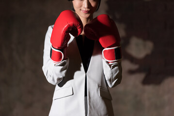A businesswoman wearing boxing gloves and striking a fighting pose.