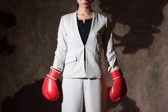 A businesswoman wearing boxing gloves and striking a fighting pose.