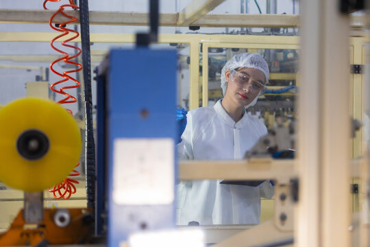 woman worker in manufacturing factory stands as inspector near industrial production equipment and machinery with serious expression checking daily operation process carefully