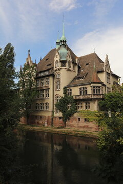 Historic building with green spires reflected in a calm river in Strasbourg