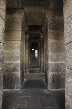 Ancient stone corridor with repeating columns and a distant window