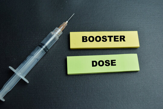 Concept of booster dose write on sticky notes isolated on table.
