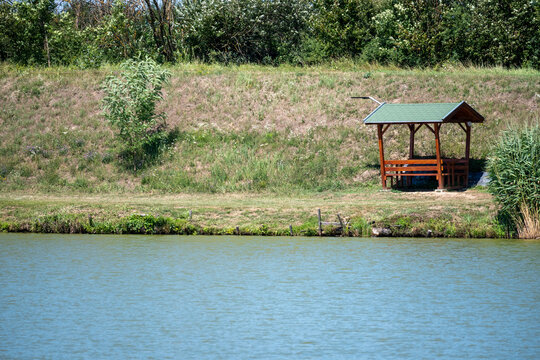Wooden Lakeside Shelter Beside Calm Water and Green Landscape