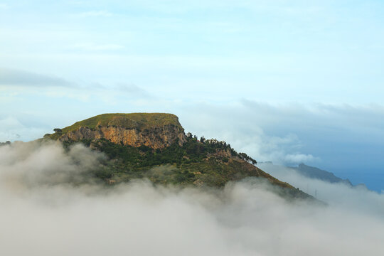 Majestic mountain peak emerges from soft clouds creating a serene natural landscape