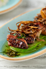 Grilled octopus tentacles with green puree, herbs and crispy onions © yalcinsonat