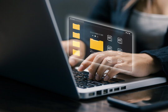 Businesswoman works on laptop with virtual folder interface, representing digital file management, cloud storage, document organization, data access, office technology, and workflow.