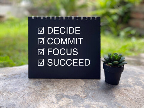 Inspirational motivational concept featuring a checklist with the words Decide, Commit, Focus, and Succeed beside a small succulent plant.