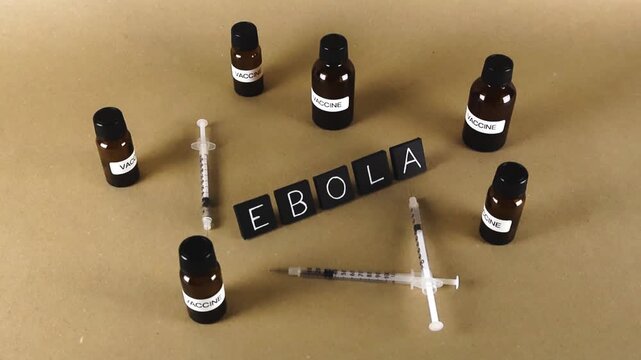Conceptual image of Ebola virus with vaccine vials and syringes on a brown background, symbolizing medical research, treatment development and global public health response