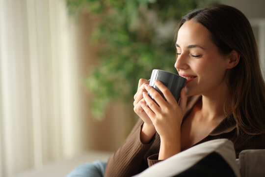 Happy woman enjoying drinking coffee at home