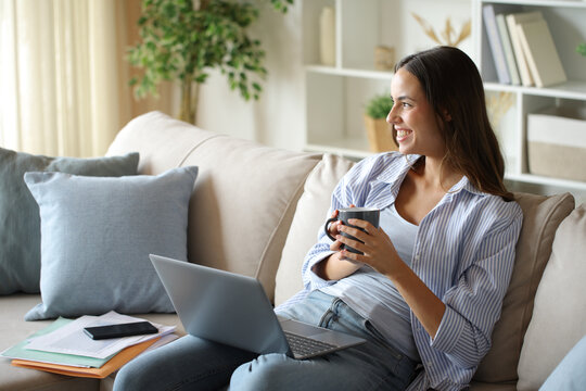 Happy teleworker holding coffee cup resting looking away