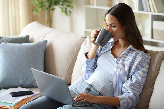Teleworker drinking coffee working online in a house