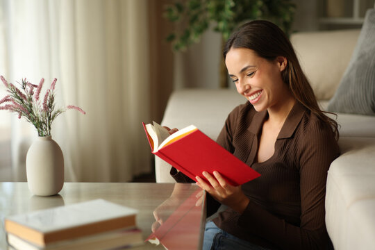 Happy woman is reading a red paper book in a house