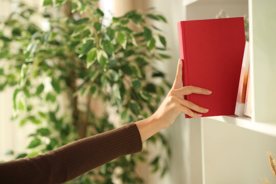 Woman hand puting paper book on a bookshelve