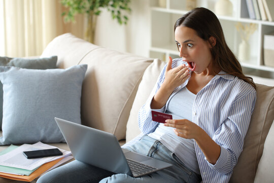 Amazed teleworker paying online with card and computer