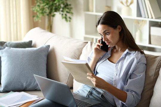 Perplexed teleworker checking report talking on phone