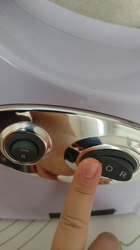 A finger pressing the power button on an electric kitchen meat grinder or juicer appliance. stock footage for kitchen gadgets, appliance operation, food prep, and cooking tutorials. close-up