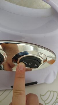 A finger pressing the power button on an electric kitchen meat grinder or juicer appliance. stock footage for kitchen gadgets, appliance operation, food prep, and cooking tutorials. close-up