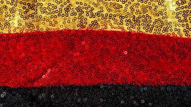 sequined fabric for German patriotic design.glittering gold, red and black sequin fabric. 4k footage