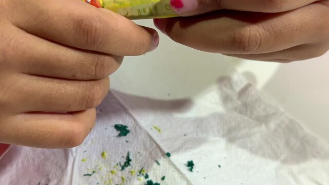 child's hands peeling wrapper off a crayon, art supplies preparation, kids creativity and coloring concept.
