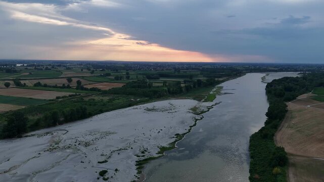 Po River shows exposed sediment and reduced water flow near Isola Serafini, Monticelli d'Ongina, Piacenza, Emilia-Romagna, Italy, South Europe, drone forward flyover.