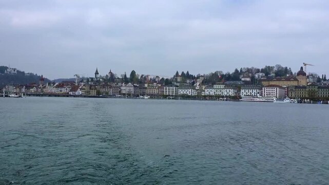 Expansive wide panning shot across Lucerne bay moving from the KKL culture convention centre past historic city spires, waterfront casinos, and terraced hillside villas.