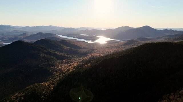 Aerial view of autumn forest, lake and mountains in Vermont with vibrant fall foliage under clear sky. g.
