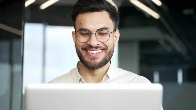Satisfied happy businessman suit received great news on laptop while sitting at workplace in business office. Smiling glad entrepreneur reads positive good message on computer. Close up. Front view