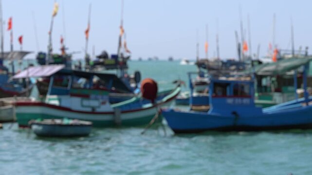 Bokeh view of Vietnamese fishing boats docked along a bustling, crowded wharf in the southern port of Nha Trang, Vietnam. Blurred background footage.