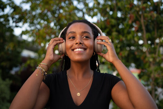 A smiling African American woman adjusts wireless audio device