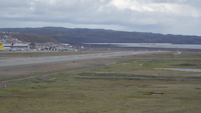 Wide-angle view showing the RAF Red Arrows aerobatic jets positioned at the threshold end of the Iqaluit Airport runway, lining up to initiate takeoff rollout.