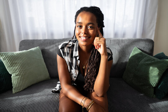 A smiling African American woman with braids sitting relaxed