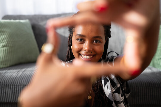 A young African American woman smiles framing her face with her hands