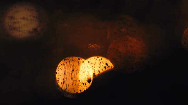 Moody rainy night scene of raindrops on a window with colorful bokeh city lights reflected and blurred, 4K