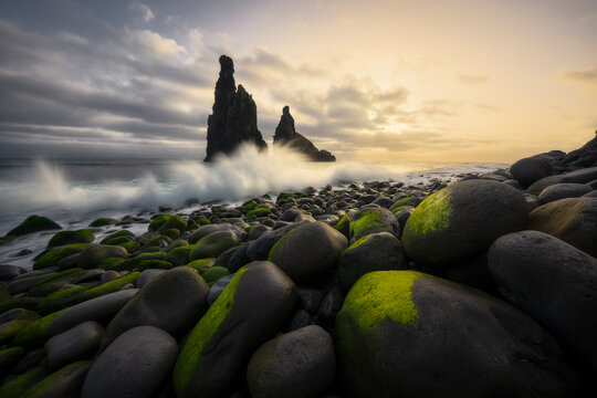 Waves crash on mossy rocky shore and sea stacks