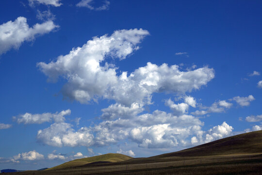 Clear Blue Sky with Fluffy Clouds and Rolling Hills