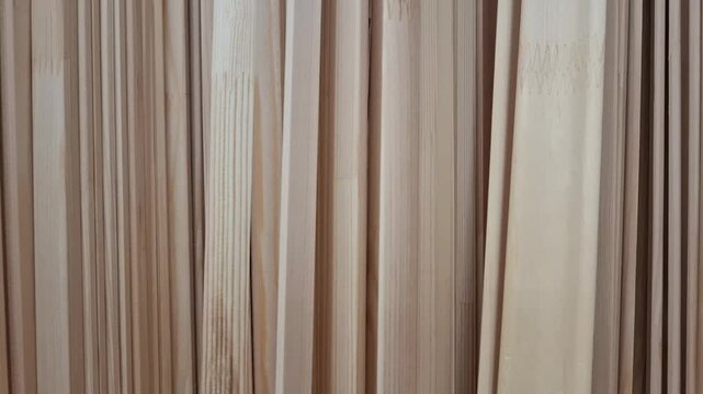 Wooden plinths and mouldings stacked vertically close up at a hardware store or workshop. Home renovation materials, interior trim supply, carpentry woodwork.